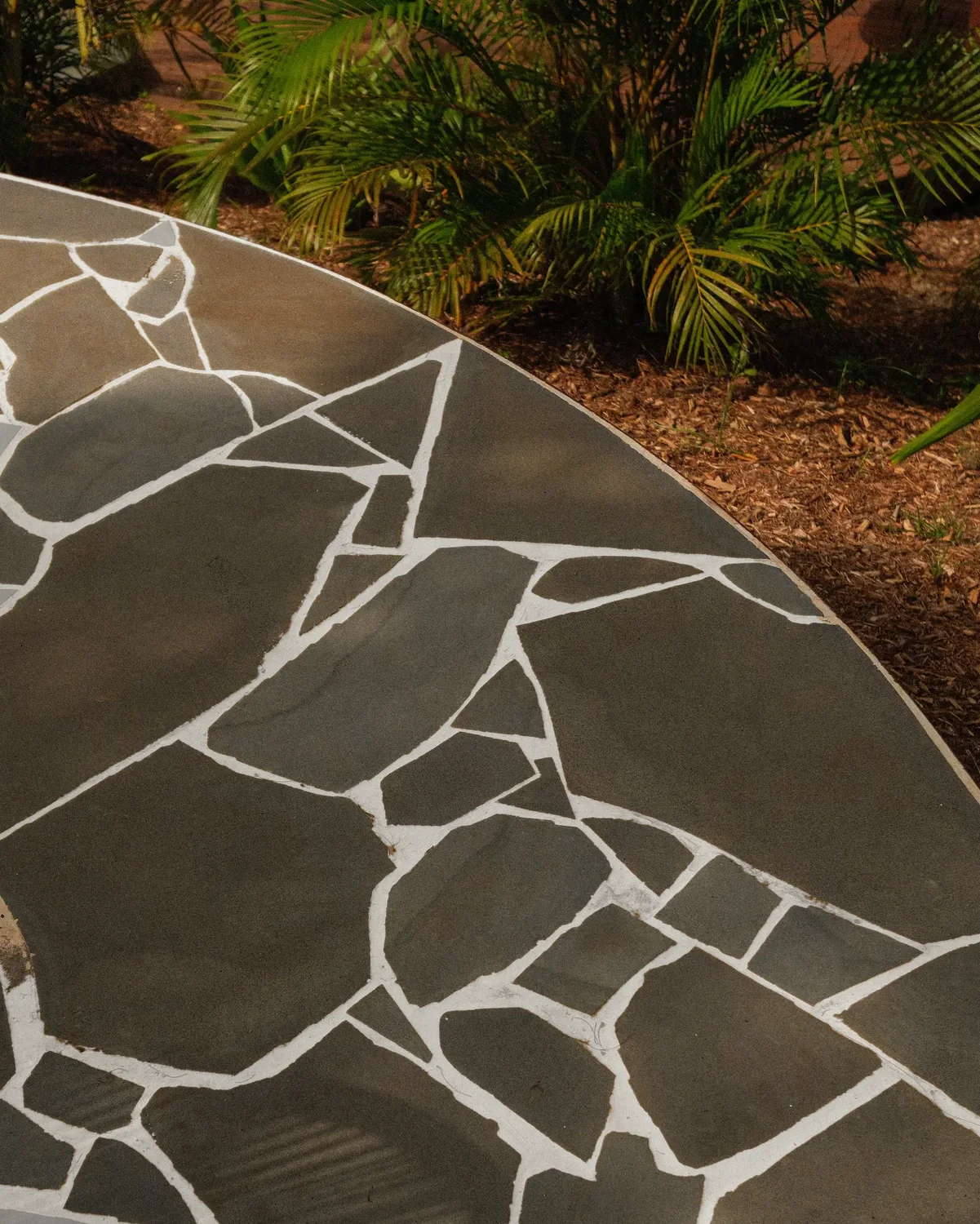 A circle of crazy paving set into mulch and planting